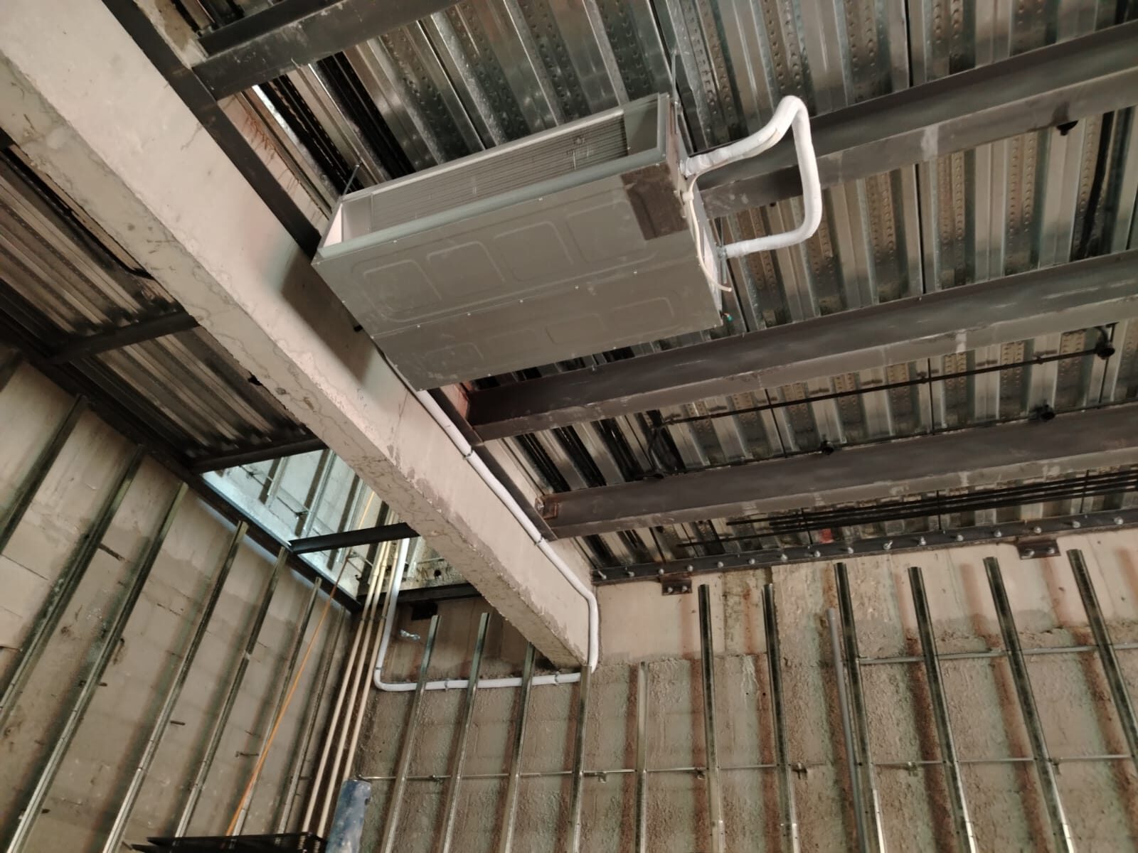 A ductwork plenum box suspended from a steel ceiling grid on a commercial site.
