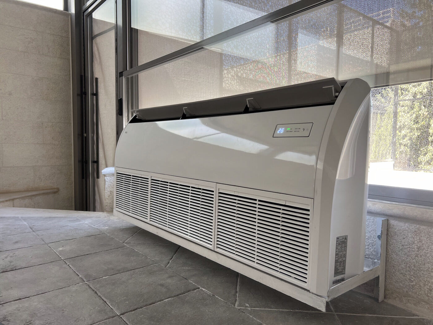A floor-standing package air conditioning unit installed on a villa balcony.