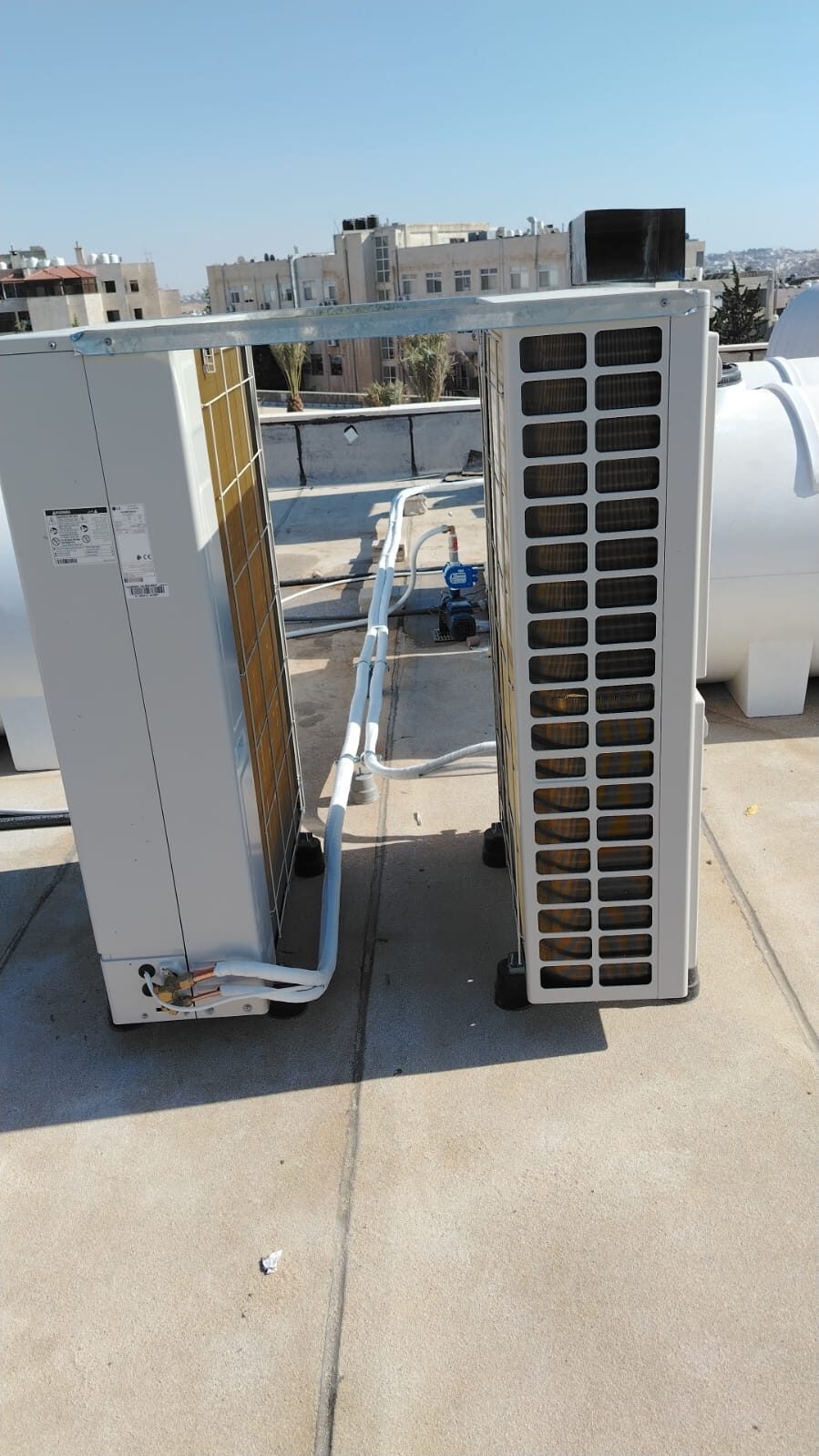 An outdoor condensing unit installed on a rooftop overlooking the city.