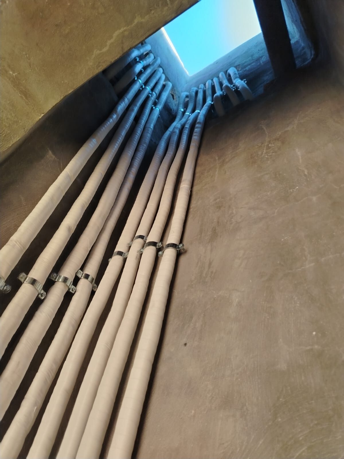 Bundled copper refrigerant lines routed through a ceiling opening.