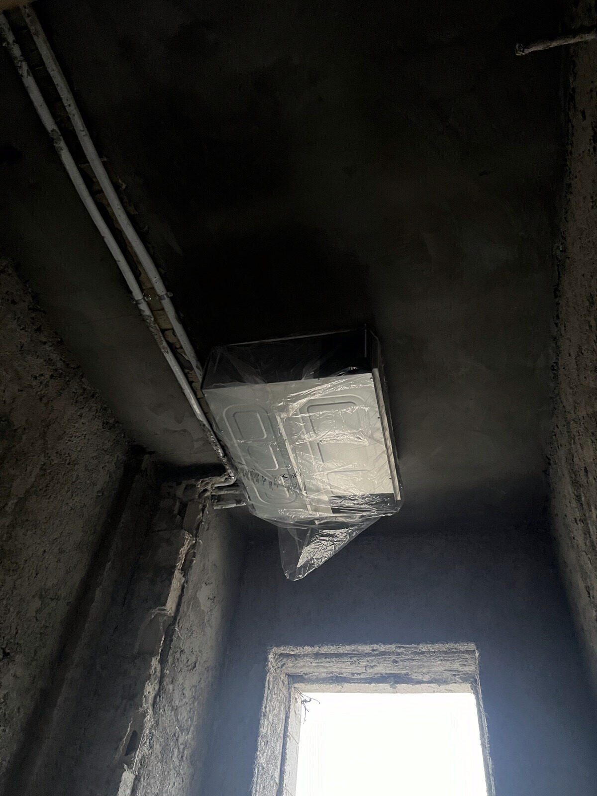 A ductwork plenum box being installed into a wall opening before finishing.