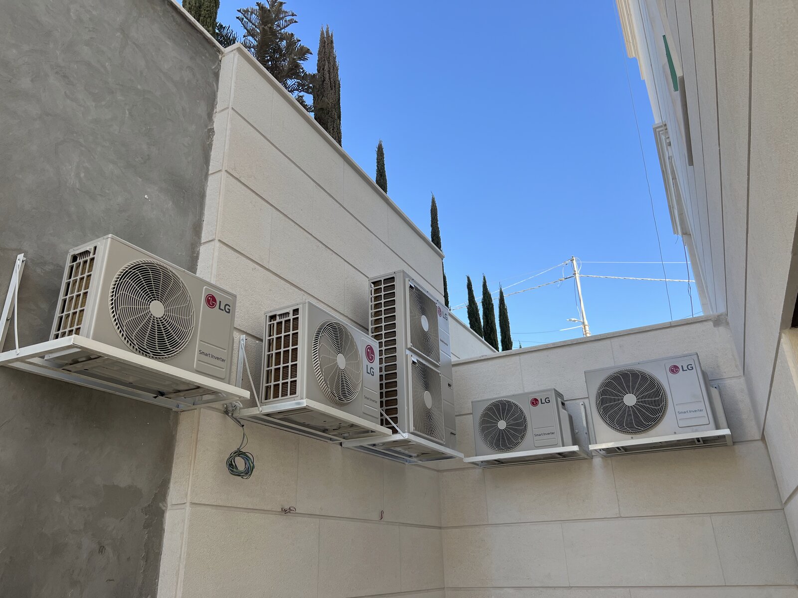 A row of LG outdoor condensing units mounted on brackets on a villa wall in Jordan.