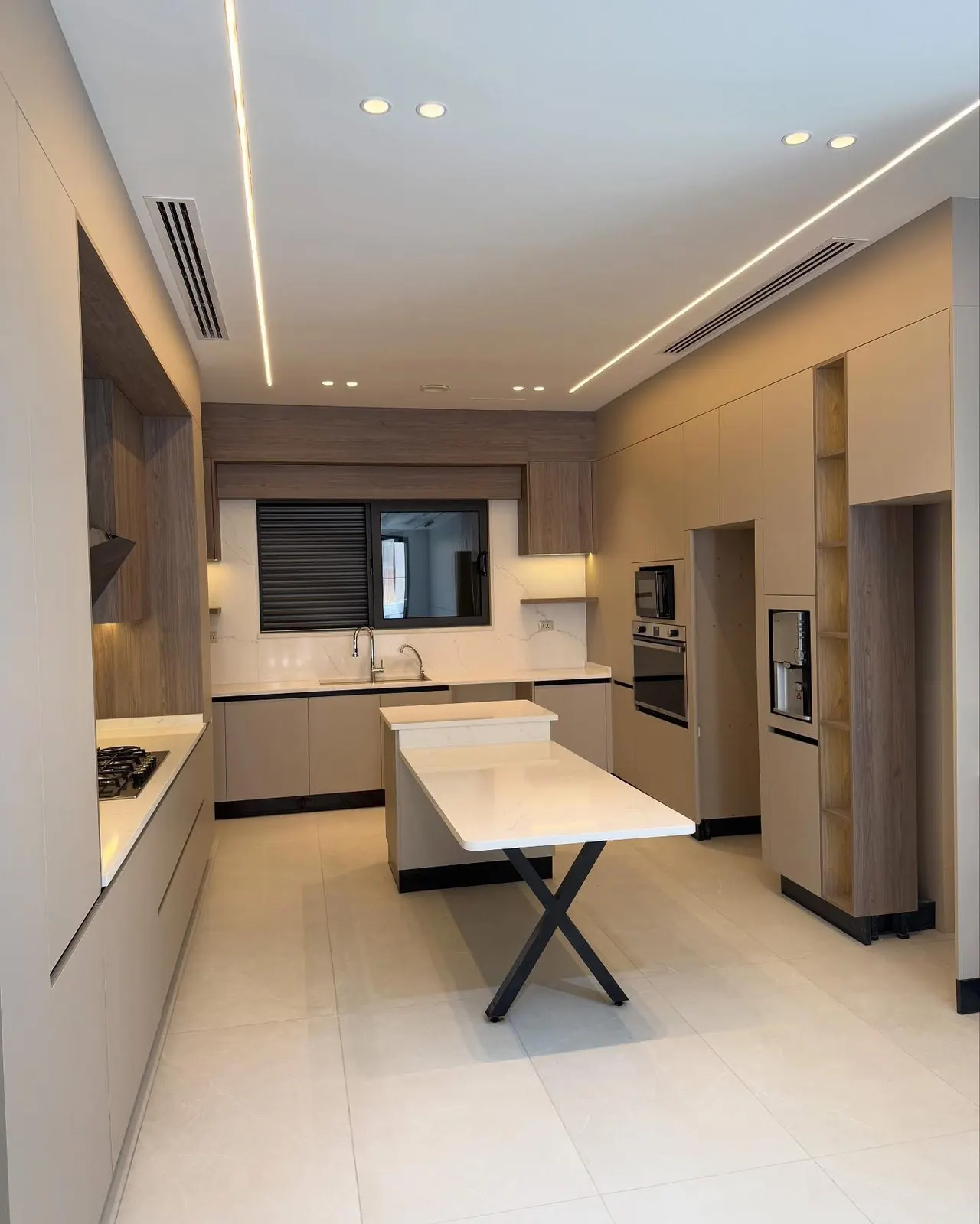A central-AC linear diffuser in the ceiling of an open-plan kitchen and living area in a finished villa in Jordan.