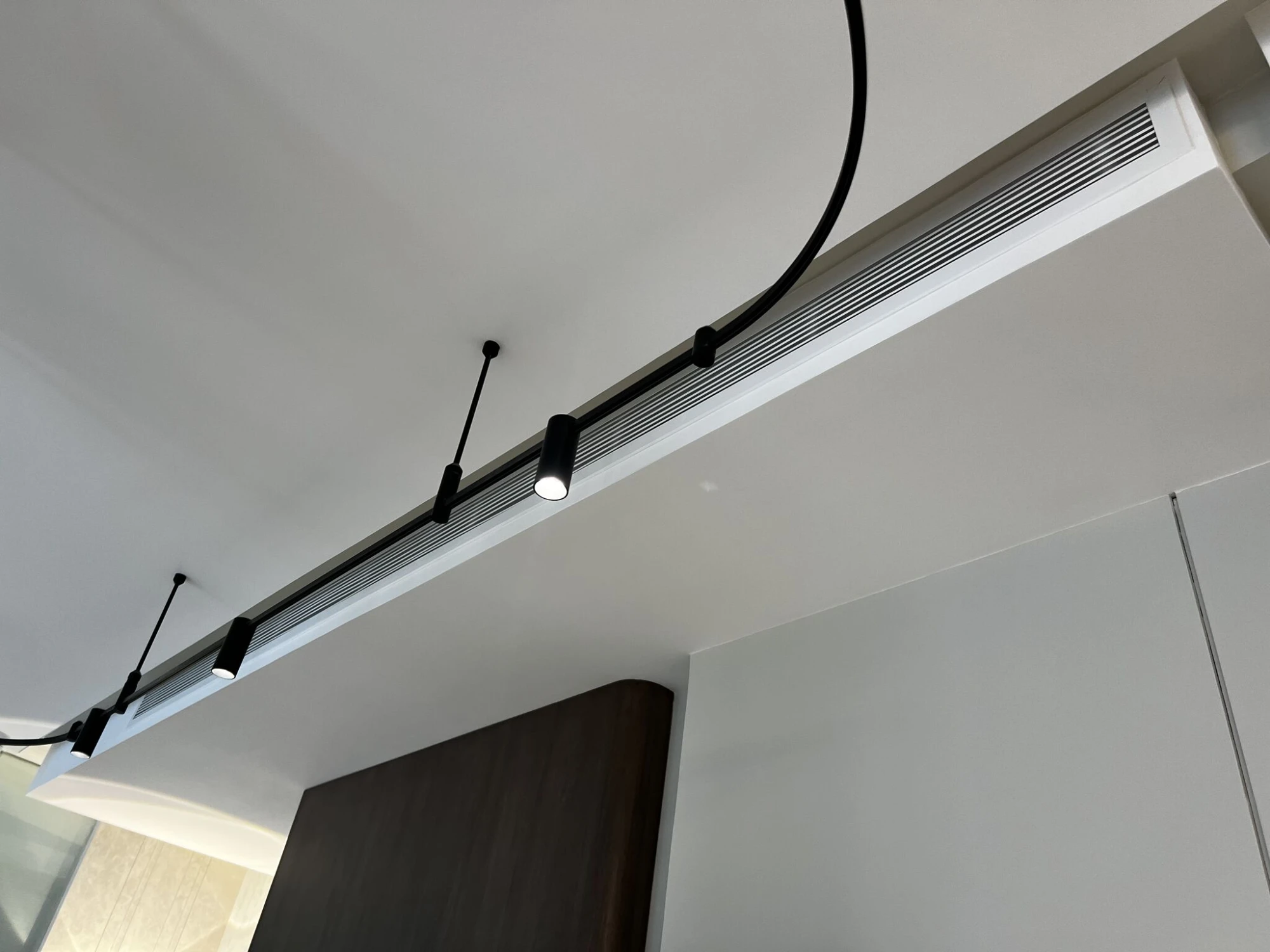 A linear grille built into the bulkhead, with the track lighting fixed along it.