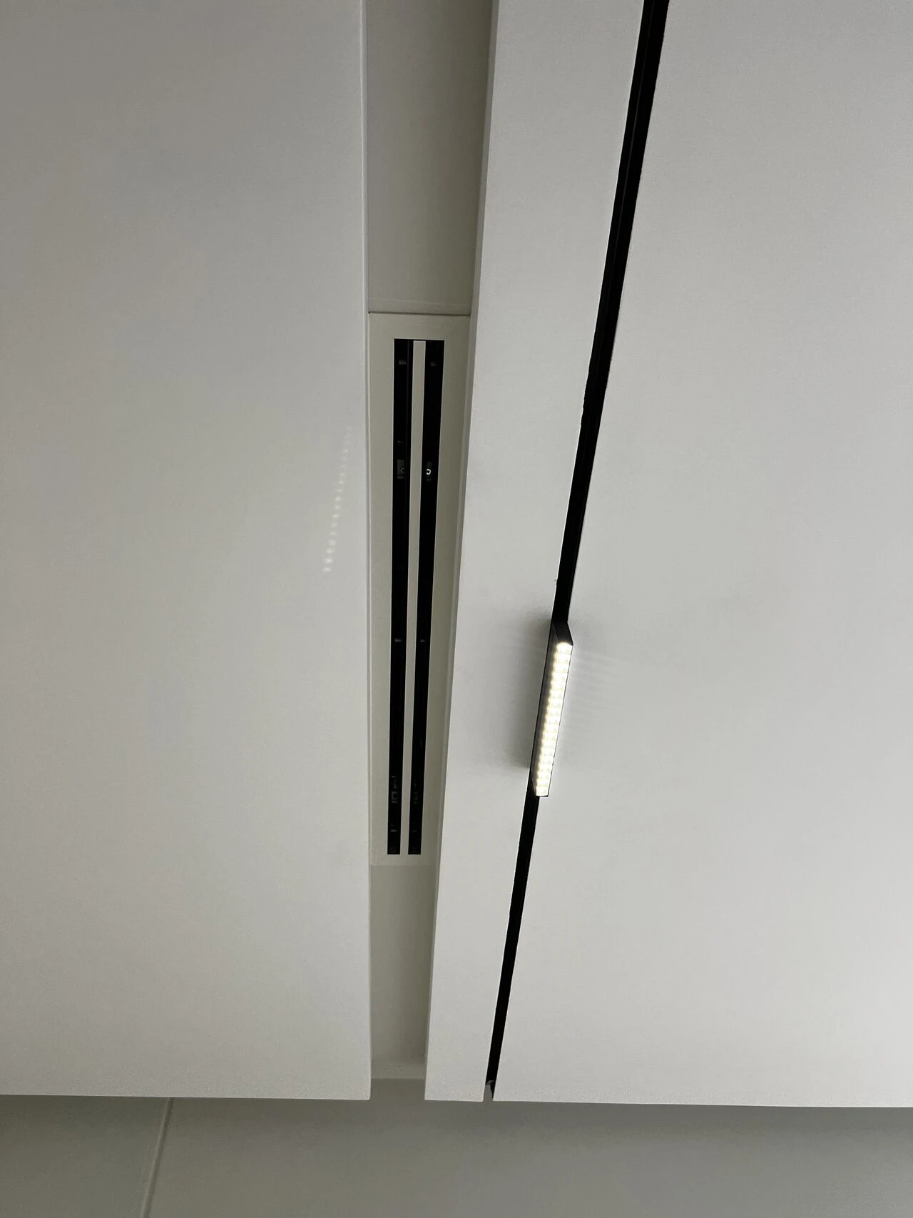 A two-slot linear diffuser beside a magnetic light track, both cut flush into the ceiling.